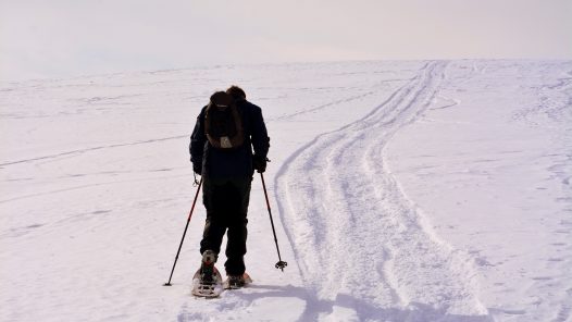 man snowshoeing up a steep snowy hill