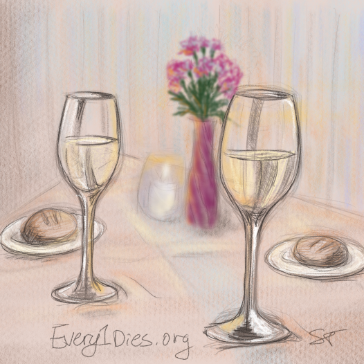 Wine glasses and food on a table set for two.