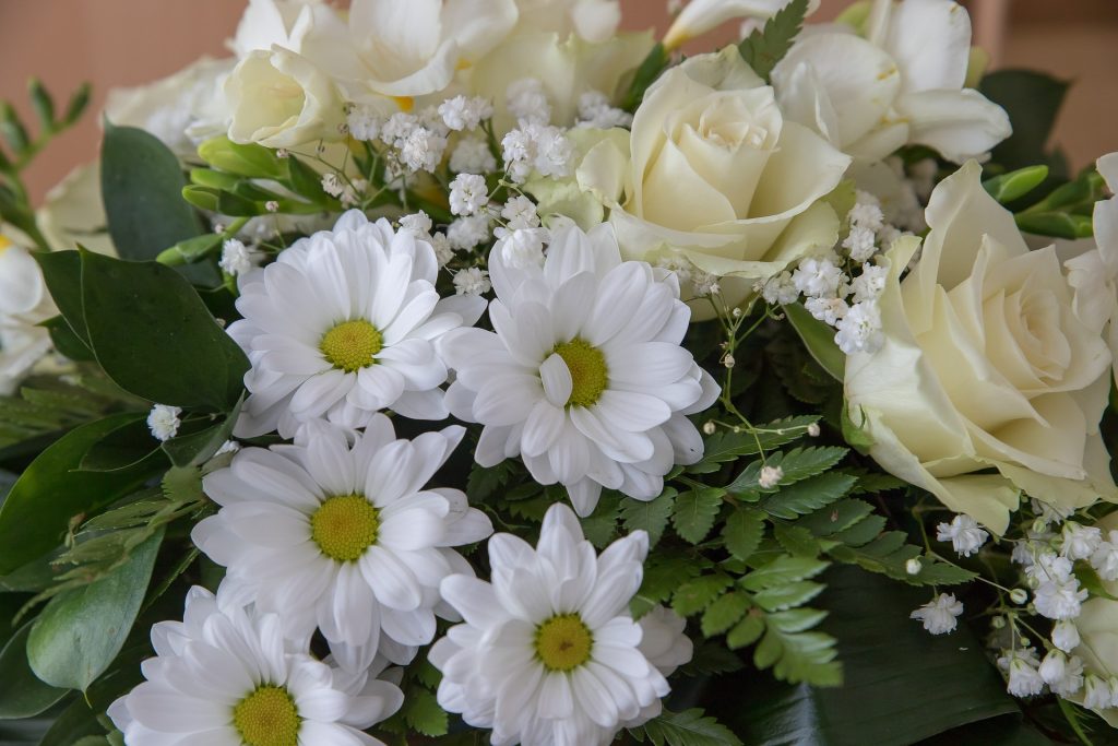 A beautiful white and cream flower arrangement at a funeral.  Learn why funerals are important at https://every1dies.org