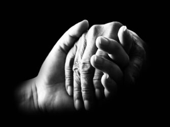 Black and white image of two people holding hands. Learn about caregiving for a partner with dementia in this episode. https://every1dies.org