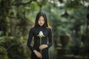 Young woman in long-sleeved black dress holding a flower. We talk about how a relationship changes when one becomes a caregiver for a partner, along with the tradition of black clothing