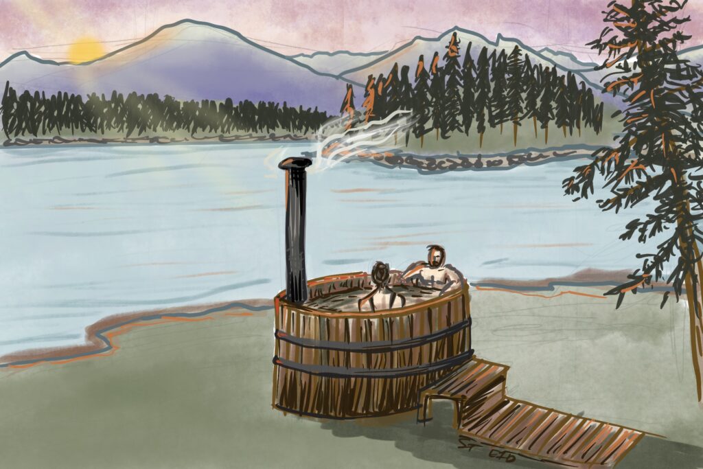 A couple enjoying a wood-fired hot tub on a lake beach with view of mountains and sunset. Learn about hot tub safety in this episode.