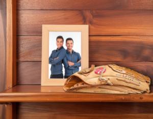 A wooden shelf with a photograph of two brothers and a worn baseball mitt. We talk about grieving the death of a sibling in this episode.