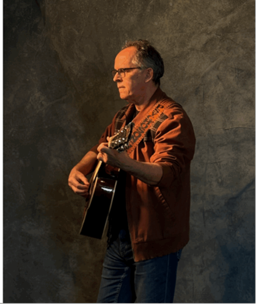 A profile image of singer/songwriter Mike Ward holding his guitar.