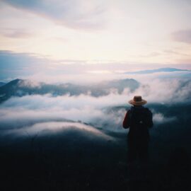 A person looking out from an overlook with mysterious clouds on the horizon