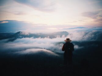 A person looking out from an overlook with mysterious clouds on the horizon