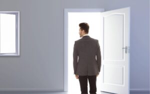 A man leaving a room through an open door. This represents the ghosting cancer patients and survivors experience by the relatives and friends they expected to support them through their journey.