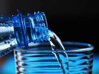 A water bottle pouring water into a glass. We talk about dehydration and its impact on cancer treatment in this episode