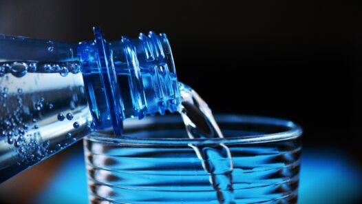 A water bottle pouring water into a glass. We talk about dehydration and its impact on cancer treatment in this episode