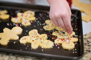 A child putting sprinkles on Christmas sugar cookies. Traditions such as these can be difficult to adapt when elders decline, but we talk about how to keep holidays special in this episode.
