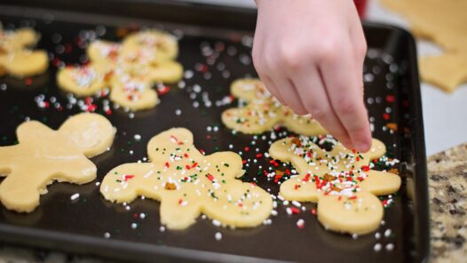 A child putting sprinkles on Christmas sugar cookies. Traditions such as these can be difficult to adapt when elders decline, but we talk about how to keep holidays special in this episode.