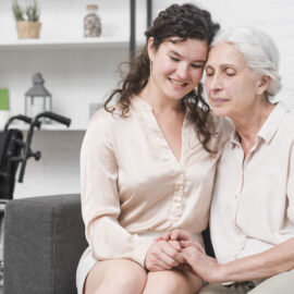A senior woman and her daughter warmly holding hands