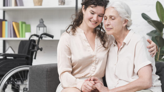 A senior woman and her daughter warmly holding hands
