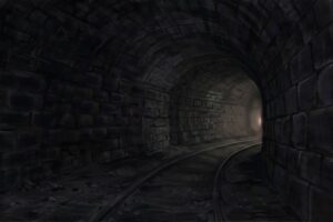 A lonely dark train tunnel with distant light.