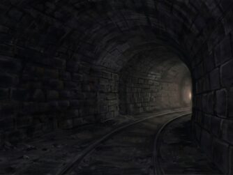 A lonely dark train tunnel with distant light.