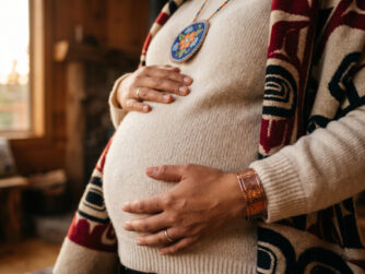 An indigenous mother in warm natural textiles holding her pregnant belly. We talk about indigenous maternal health in this episode.