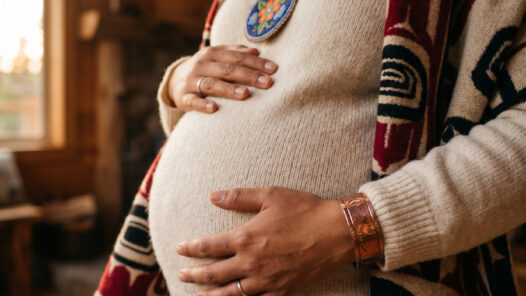 An indigenous mother in warm natural textiles holding her pregnant belly. We talk about indigenous maternal health in this episode.