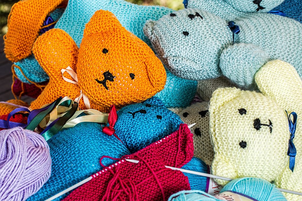 Knitted teddy bears in various colors, with bundles of thread and knitting needles. We talk about ikigai and how setting small, meaningful goals, immersing in an activity and reaching a flow state, looking outward, and allowing yourself pleasure can help in navigating grief